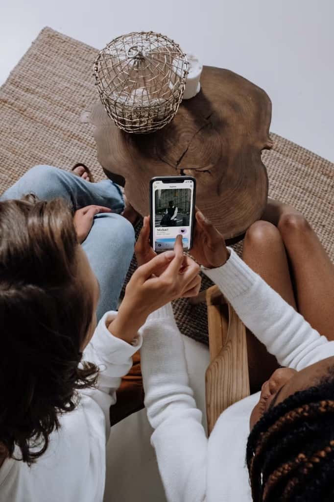 Two people looking together at a dating profile on a phone.