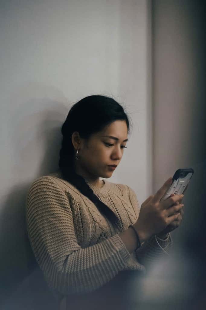 A woman reading a phone, her face partly in shadow.